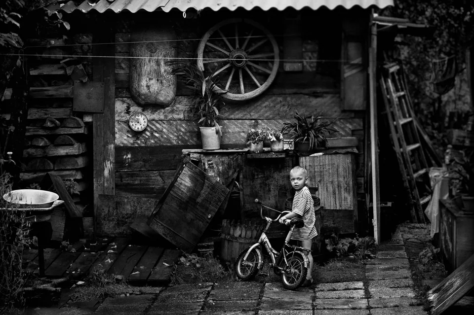 Black and white candid scene capturing everyday life - child with bike.