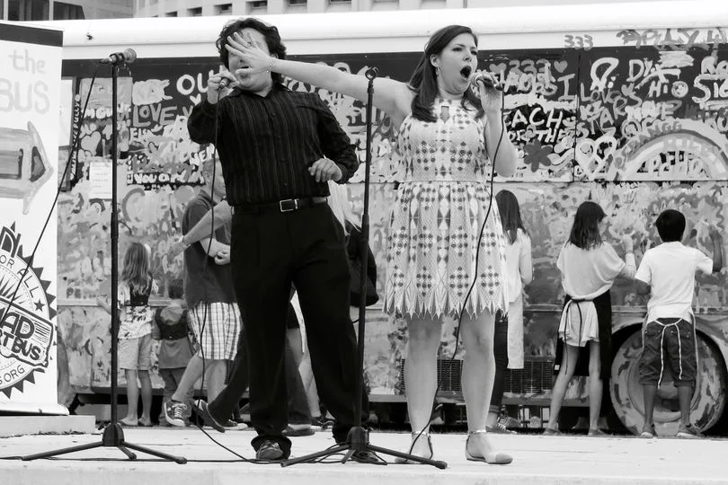 Candid black and white street photo of singer stealing the limelight.