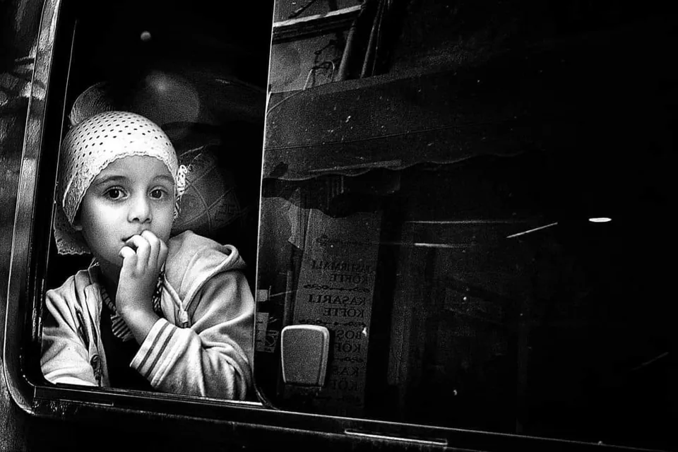 Street photography in black and white, capturing a contemplative child on a bus.