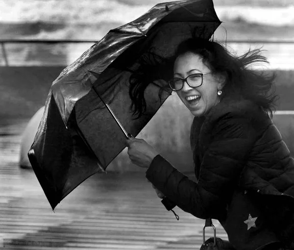 Urban street photography showing girl with umbrella in a rainstorm.
