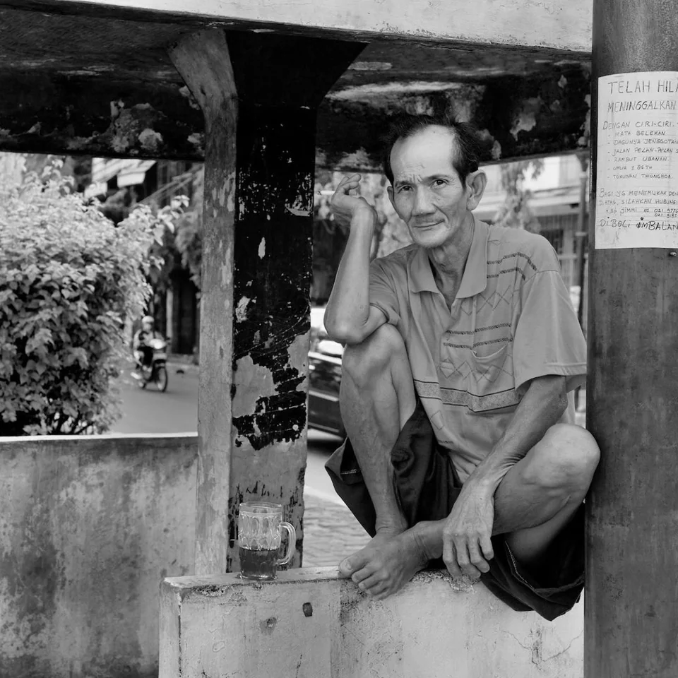 A man seated outside a street-side shop — photograph by Peter Pickering