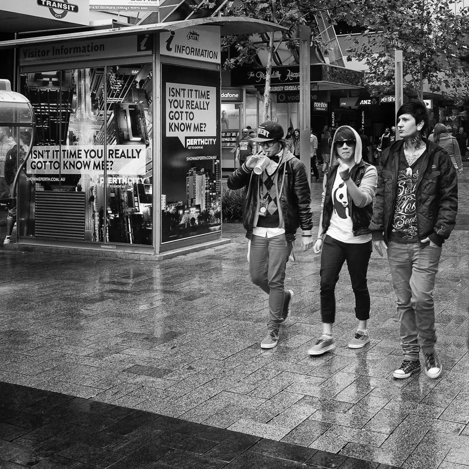 Three people walking through a city shopping area — photograph by Peter Pickering