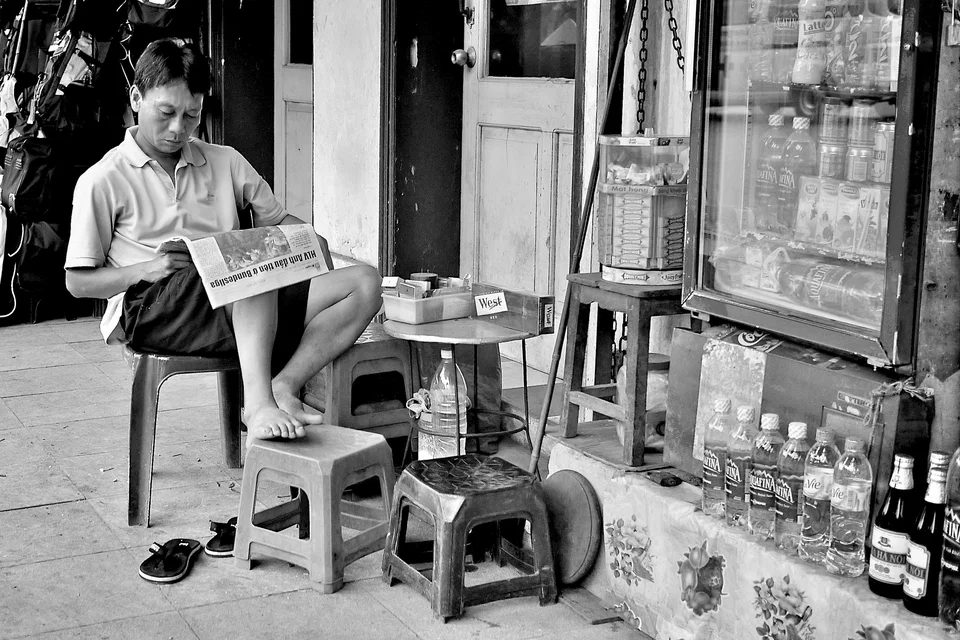 A seated man and small stools outside a shop — photograph by Peter Pickering