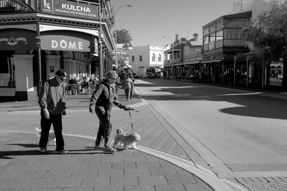 People cross a broad city street — photograph by Peter Pickering