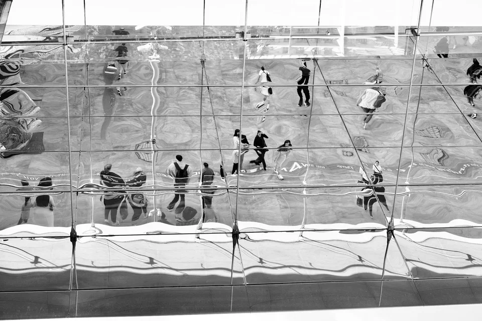 People reflected in a rippling mirrored façade — photograph by Peter Pickering