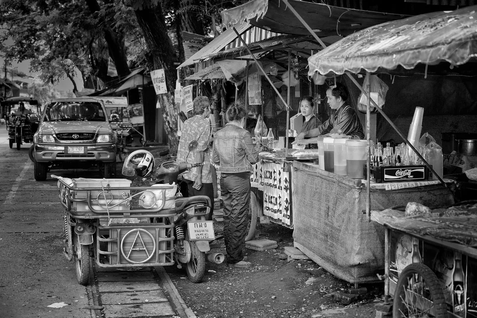 A motorised cart passes a busy market stall — photograph by Peter Pickering