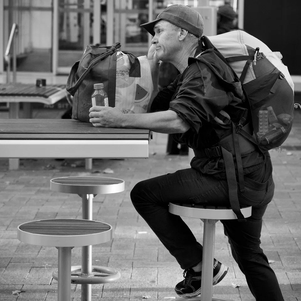 A man leans towards a café table — photograph by Peter Pickering