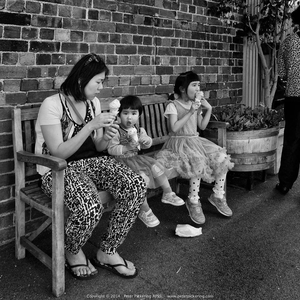 A woman and children sit on a bench — photograph by Peter Pickering
