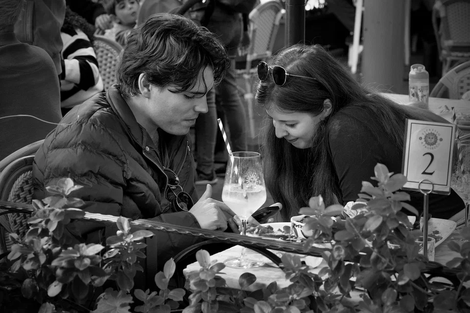 Two people lean towards a café table — photograph by Peter Pickering