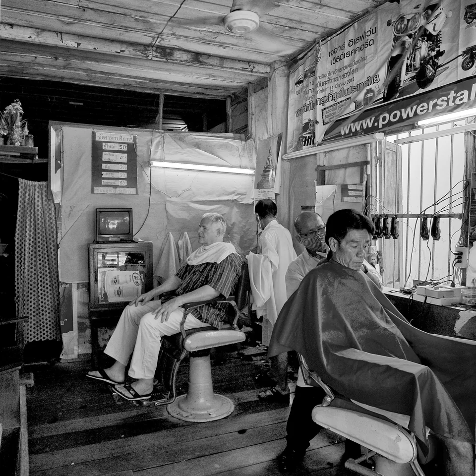 Customers and a barber inside a small shop — photograph by Peter Pickering