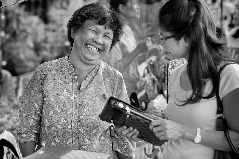 Two women share a smile in a street-side encounter — photograph by Peter Pickering