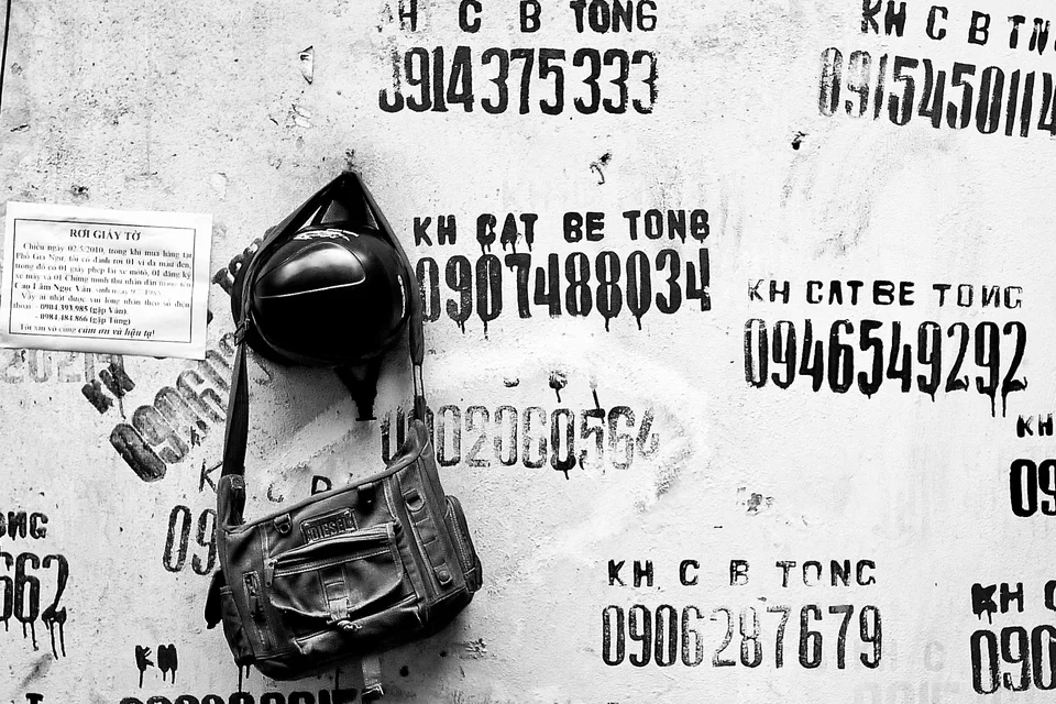 A helmet and bag hang against a wall covered in lettering — photograph by Peter Pickering