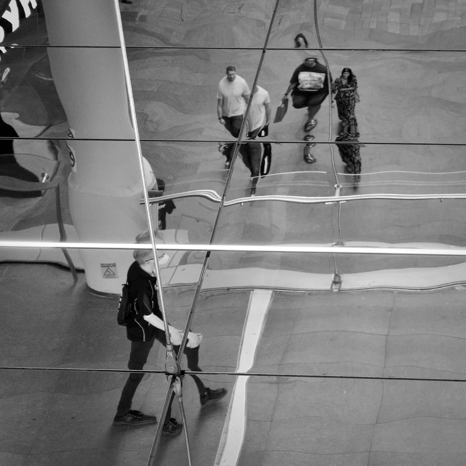 Figures and architectural lines reflected in a curved surface — photograph by Peter Pickering