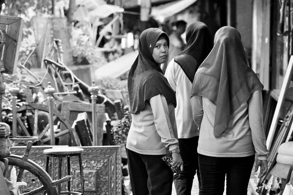 A woman looks back in a busy market street — photograph by Peter Pickering