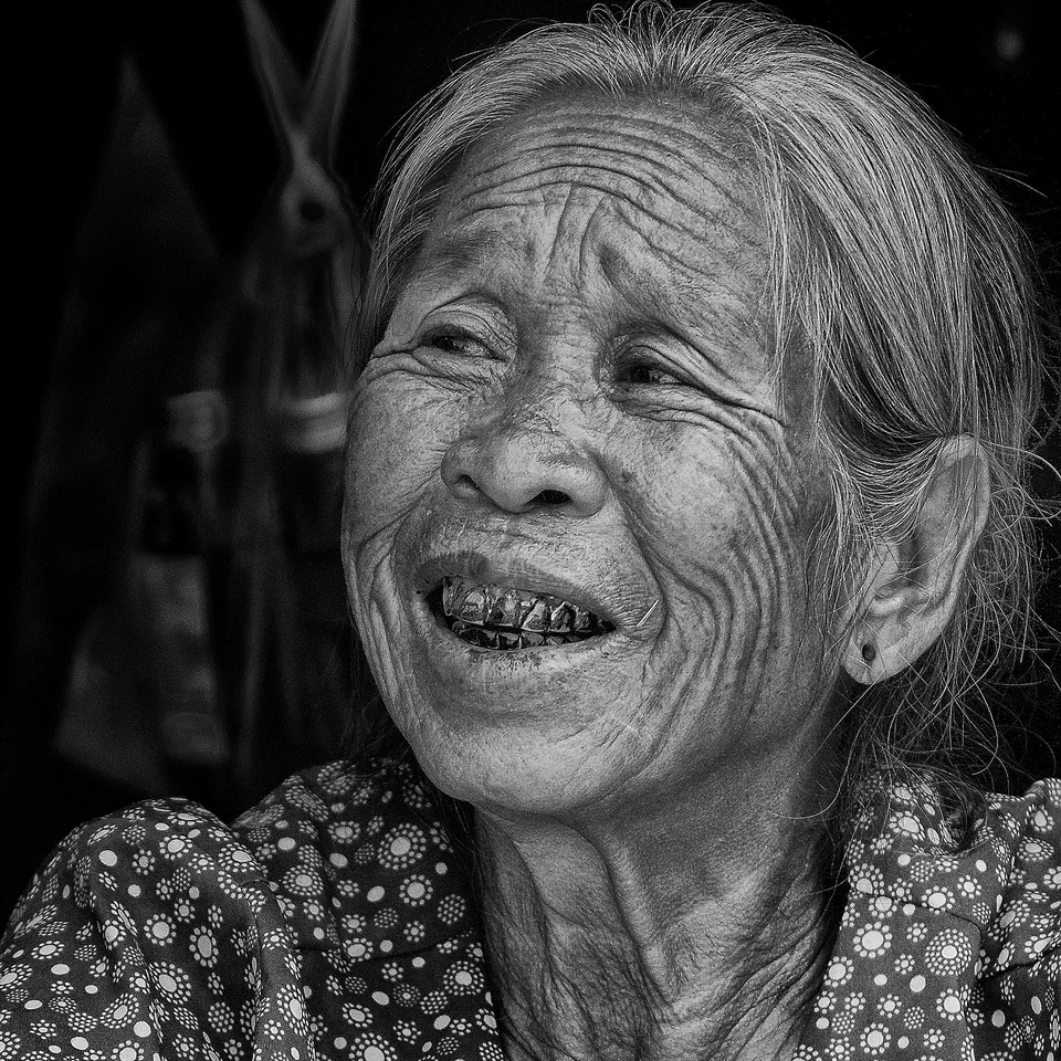 An older woman smiles against a dark background — photograph by Peter Pickering