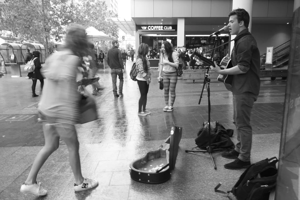 Passers-by move past a street musician — photograph by Peter Pickering
