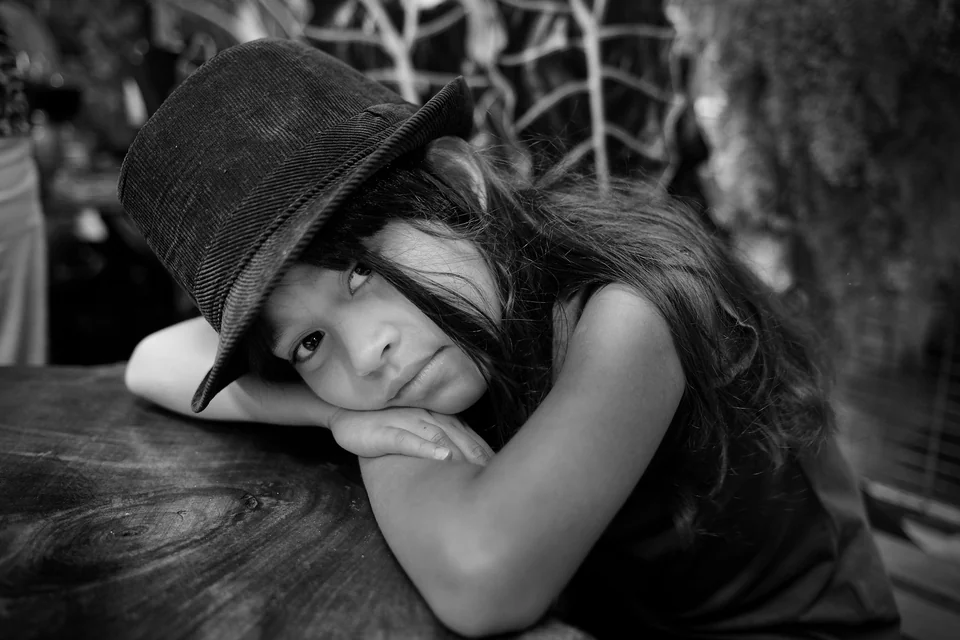 A child rests her head on folded arms — photograph by Peter Pickering