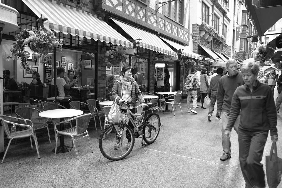 A cyclist passes outdoor café tables — photograph by Peter Pickering