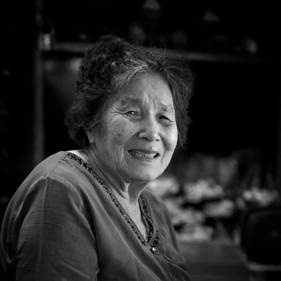 A woman smiles in the doorway of a market stall — photograph by Peter Pickering