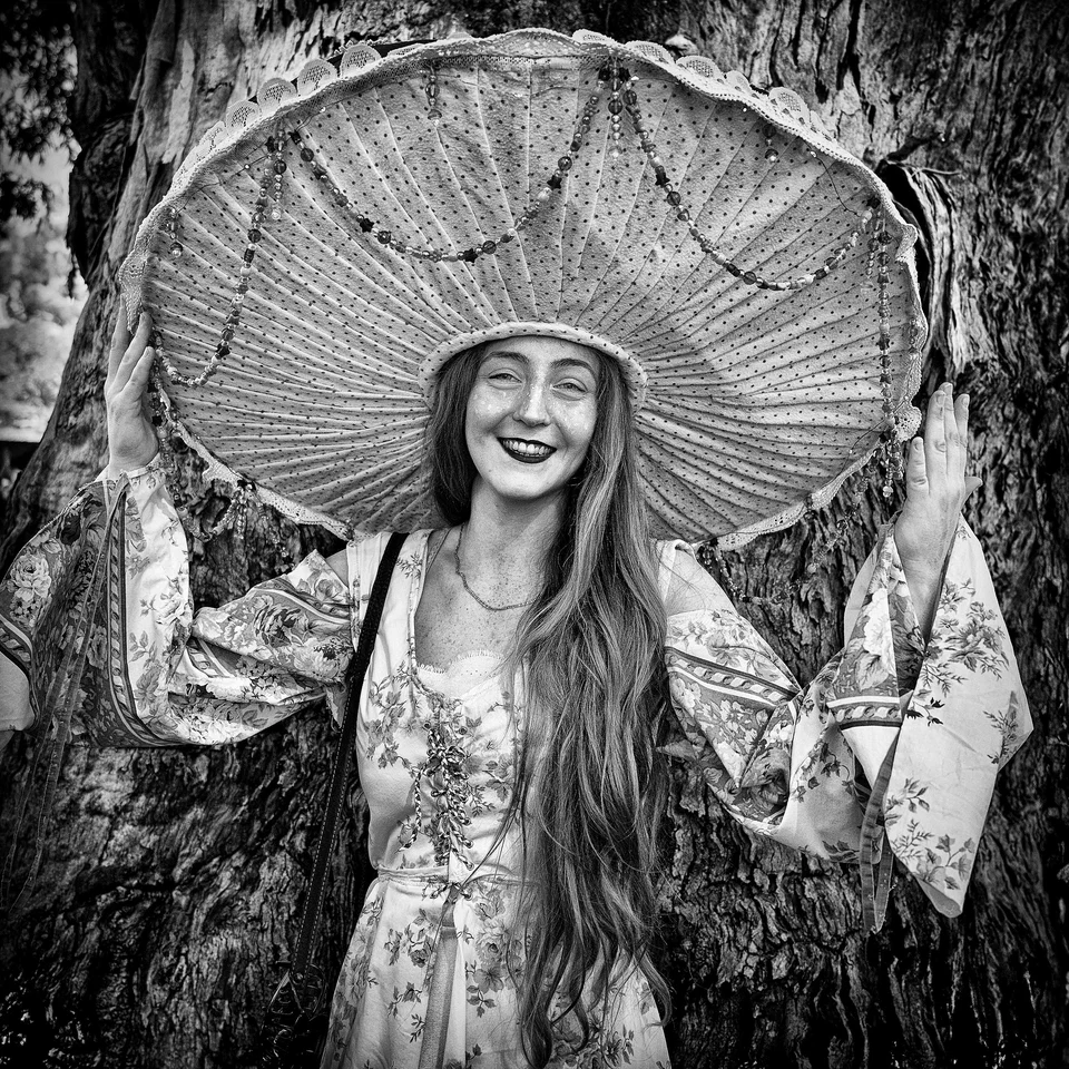 A smiling woman holds a parasol above her head — photograph by Peter Pickering