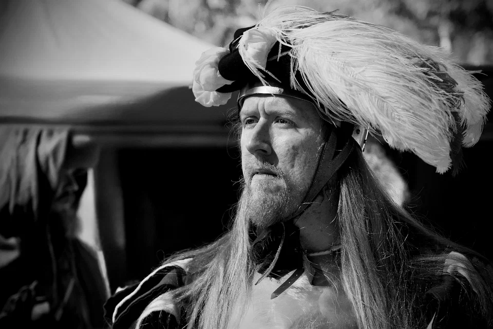 A costumed man wears a large feathered hat — photograph by Peter Pickering