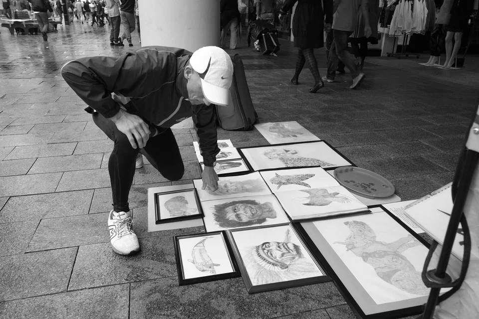 A person bends to inspect drawings displayed on the pavement — photograph by Peter Pickering